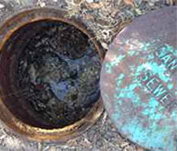 Bronze Sewer Cap open to Show Clogged Drain