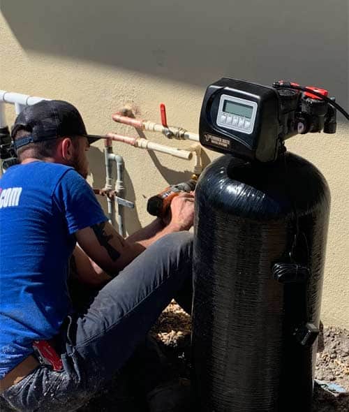 Plumber installing a water filtration system outside a Sarasota home