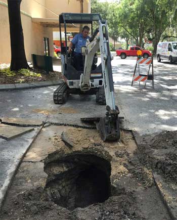 Plumber using a back hoe on a commercial sewer repair