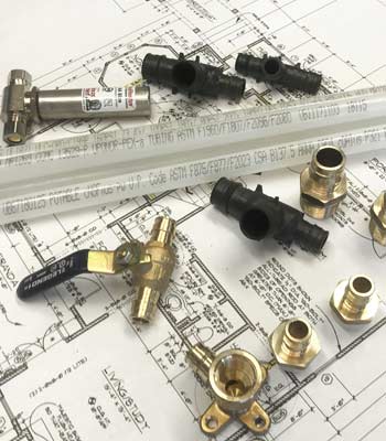 PEX pipes, fittings, and valves on top of construction prints - Commercial Re-Pipes