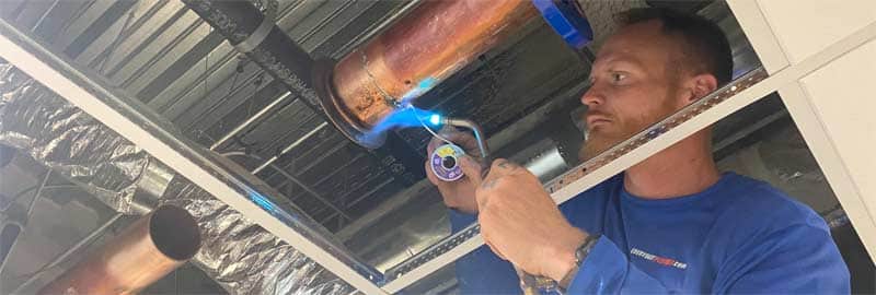 Plumber welding a 4" copper water supply pipe - Commercial Re-Pipes