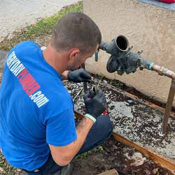 Plumber repairing an emergency leak on a backflow prevention device