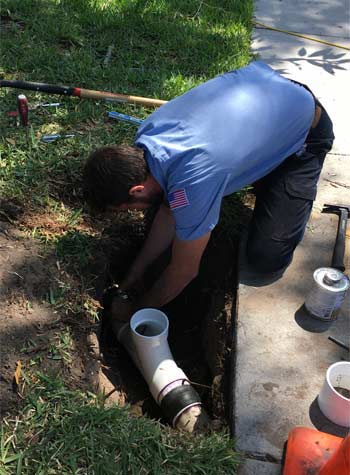 Plumber repairing a 4" PVC sewer line.