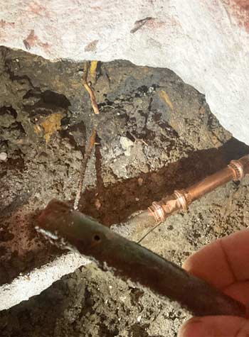 Repair of Copper Pipe Under Concrete - Plumber Showing Old Pipe With Hole In It.