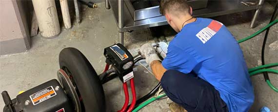 Plumber using a drain cable machine to clear a clogged drain