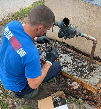 Plumber from EVERYDAYPLUMBER.com making an emergency plumbing repair on a backflow preventer in Sun City Center, FL