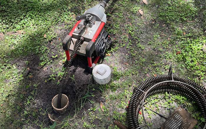 Rigid K-60 Drain Cleaning Cable Machine in a sewer line clean-out in a yard in Clearwater, FL