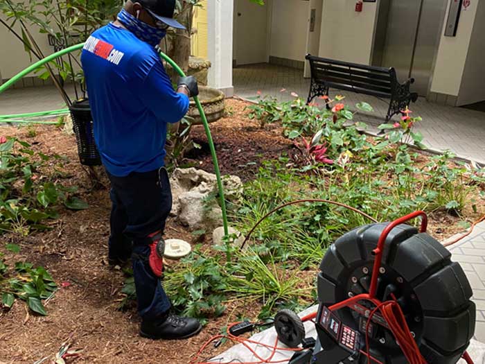 Plumber using a hydro-jetting machine to clean a sewer line.