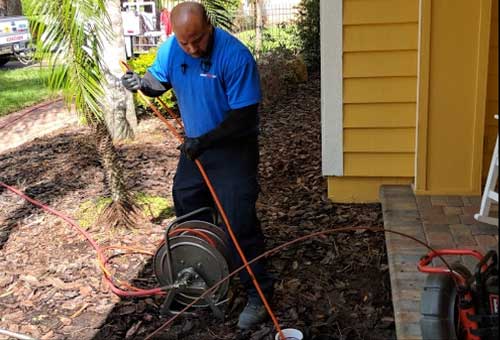 Plumber cleaning a drain from an outside clean out.