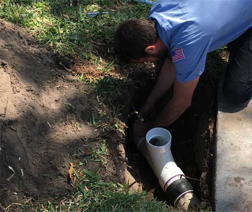 EVERYDAYPLUMBER.com plumber repairing a sewer pipe in the yard of a Tampa home.