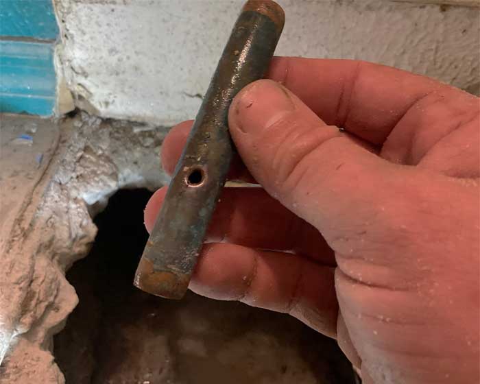 Plumber holding a copper pipe with a pinhole leak in it that was repaired under the slab of a home in Tampa, FL