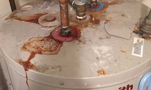 Older water heater with rusty water stains,