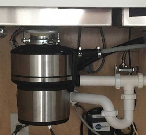 Plumbing tips - Stainless steel garbage disposal and PVC tubular pipes under a kitchen sink