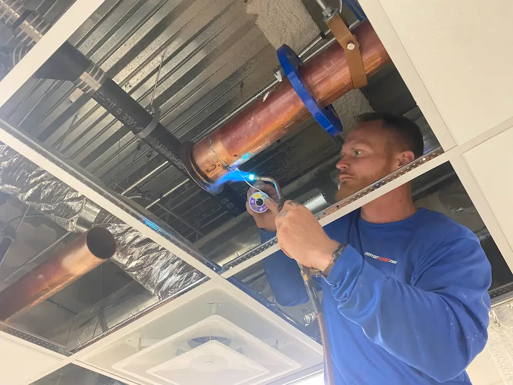 Plumber heating copper pipes during a commercial plumbing repair in Hillsborough County.