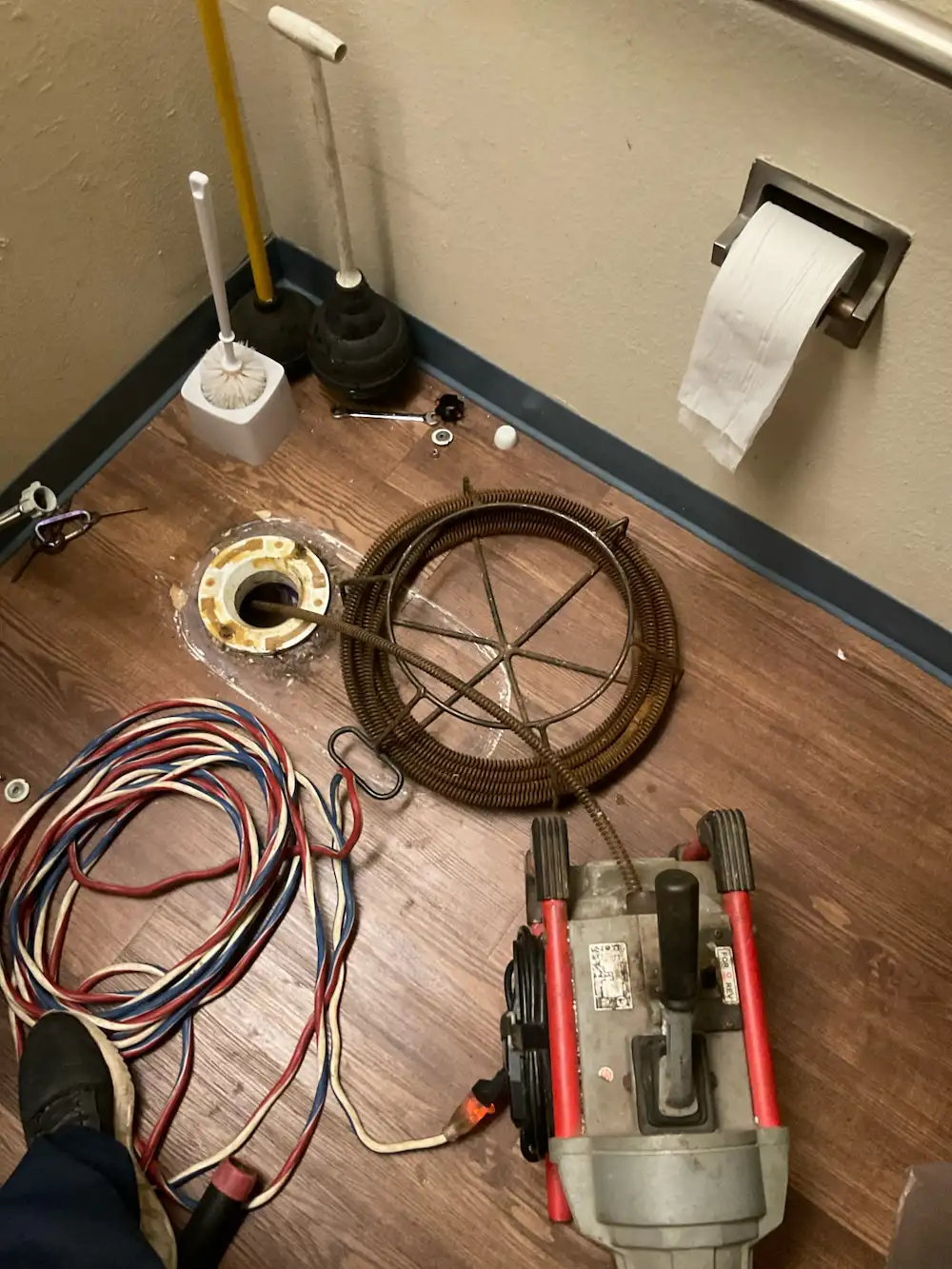 Plumber’s drain snake and equipment used to clear a toilet clog after removal in a Hillsborough County commercial bathroom.