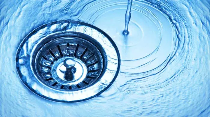 Water flowing into a clean metal sink drain