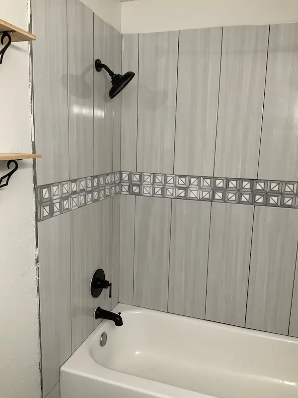 Bathtub and shower wall with new tile and fixtures after professional shower plumbing repair and installation