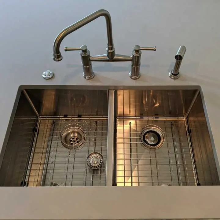 Modern double-basin stainless steel kitchen sink with gooseneck faucet and sink grids.