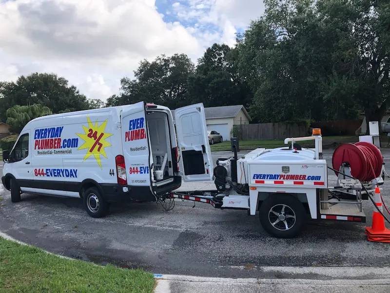 Hydro jetting trailer and service van staged at the curb for residential sewer line cleaning in a North Tampa neighborhood.