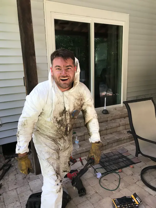 Plumber in full protective coveralls and gloves, covered in dirt after completing a messy plumbing job in Tampa, Florida.