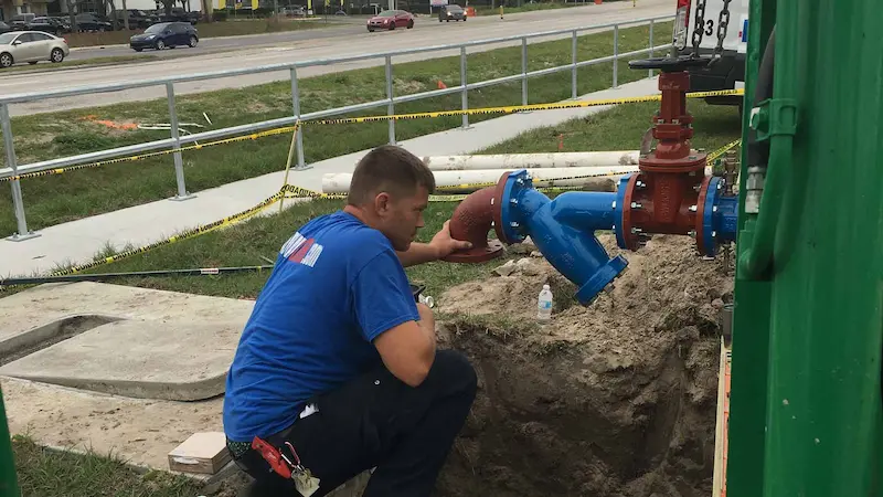 Technician installing a commercial backflow preventer on a water main in St. Petersburg for EVERYDAYPLUMBER.com