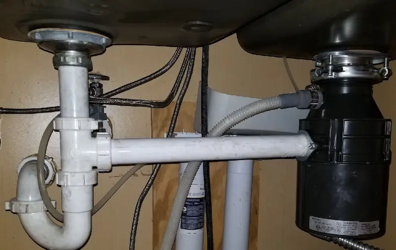 New garbage disposal installed under kitchen sink with connected drain and dishwasher hose by St. Petersburg plumbers at EVERYDAYPLUMBER.com