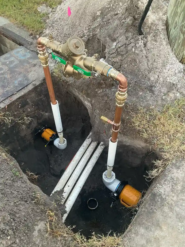 Backflow prevention device newly installed with copper and PVC piping during a plumbing project in a Tampa yard