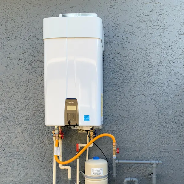 Navien tankless water heater mounted on an exterior wall with gas and water lines, isolation valves, and an expansion tank in Cheval, FL.