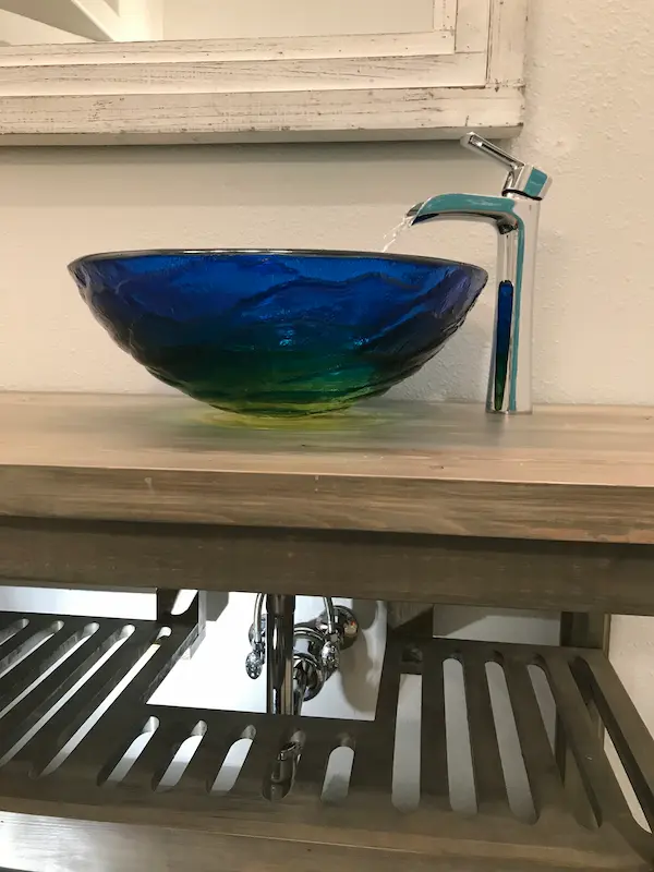 Blue glass vessel sink and modern faucet on a bathroom vanity, residential plumbing in Ybor City