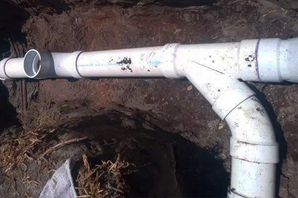 New PVC sewer line with wye fitting and vertical cleanout installed in trench with proper slope and glued joints