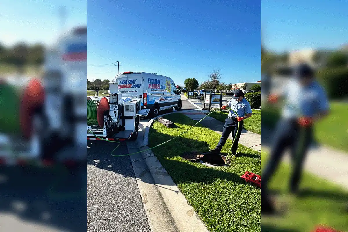 EVERYDAYPLUMBER.com uniformed technician operating hydro jetting equipment with branded van and trailer at commercial job site in Tampa Bay
