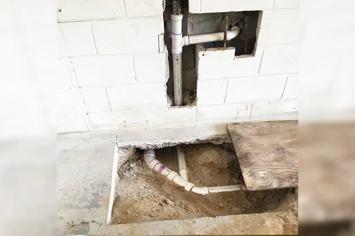 New Schedule 40 PVC drain lines installed through a concrete block wall and under-slab excavation during a commercial sewer repair by EverydayPlumber.com in Tampa Bay