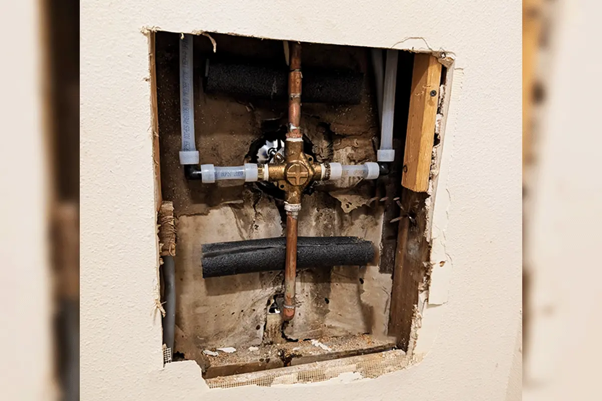 Wall access opening showing new PEX supply lines transitioning to copper fittings during a whole house repipe by EverydayPlumber.com in Tampa Bay