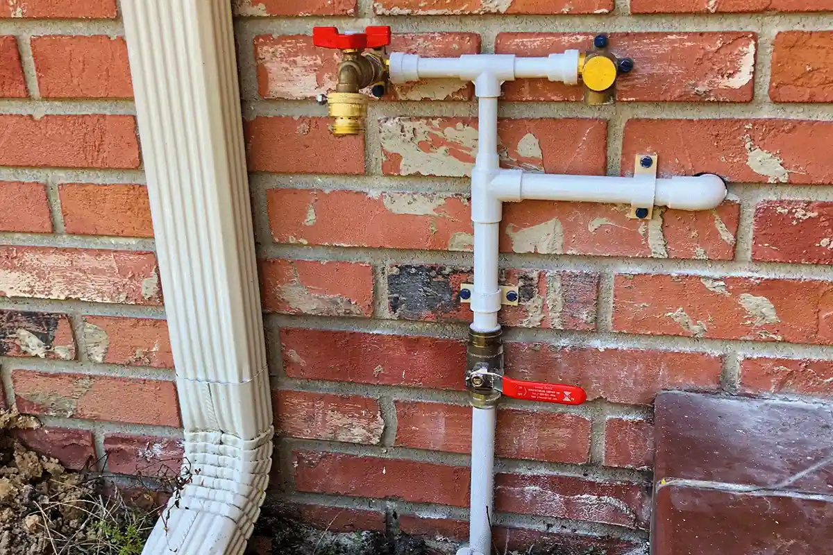 New CPVC outdoor pipe installation with brass ball valves mounted on exterior brick wall — EVERYDAYPLUMBER.com Tampa Bay
