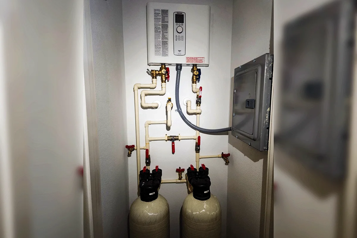 Tankless water heater installed above dual whole-home water softener tanks — tankless water heater and water softener installation Tampa