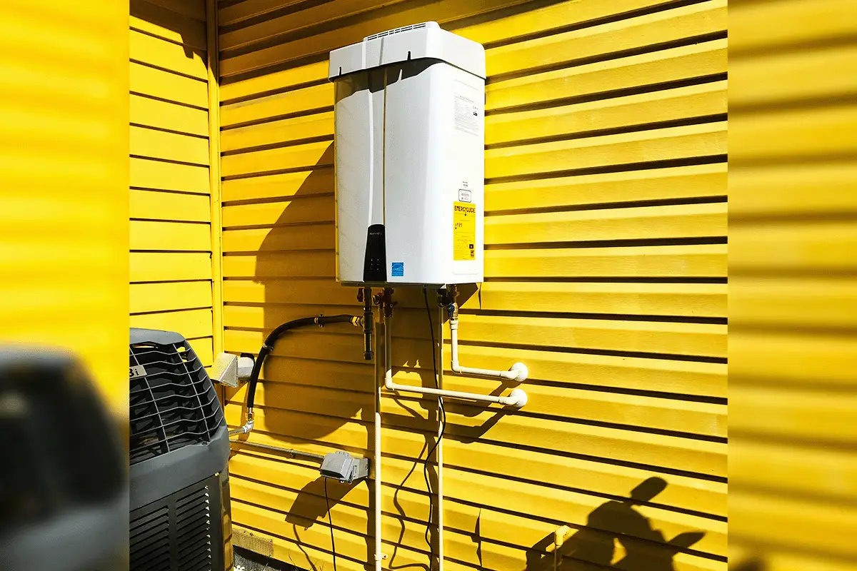 Tankless water heater mounted on exterior wall with PVC supply lines — tankless water heater installation Tampa