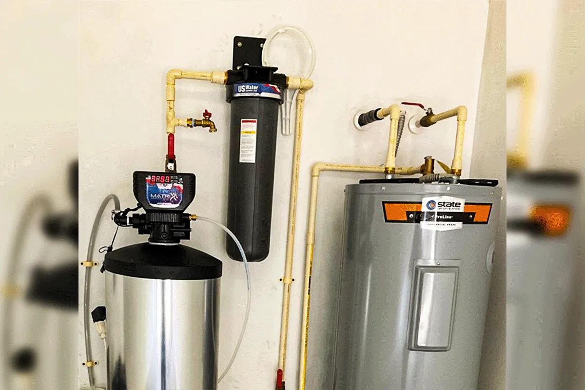 Water softener and whole-house carbon pre-filter installed alongside tank water heater — combination water treatment system