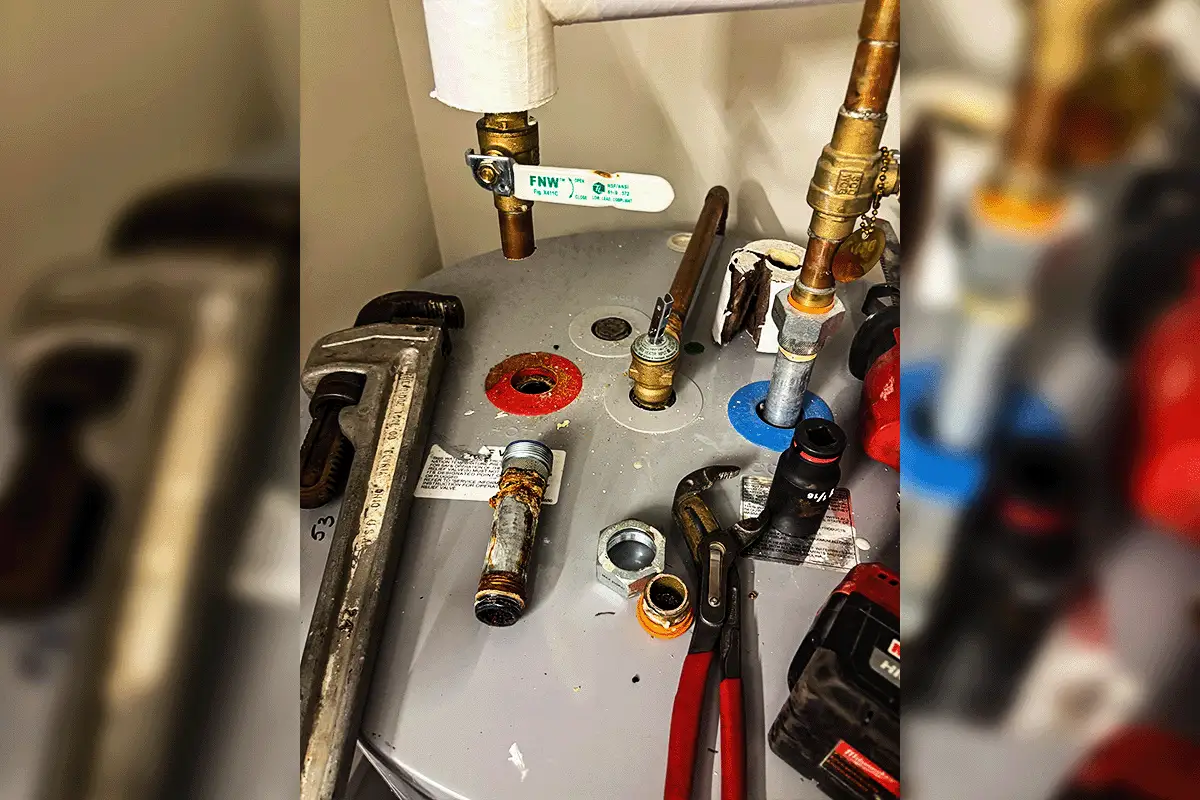 Active water heater repair in progress at a Tampa Bay home — top of tank showing corroded anode rod removed, new FNW ball valves installed on inlet and outlet connections, Milwaukee tools and channel locks laid out during an EverydayPlumber.com diagnostic and repair service call