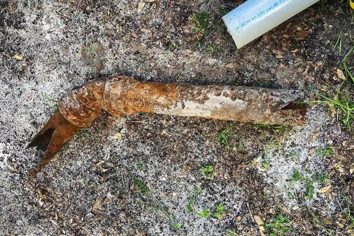 Heavily corroded cast iron drain pipe removed from South Tampa residential yard alongside new PVC replacement — pipe repair and repiping services in South Tampa — EVERYDAYPLUMBER.com