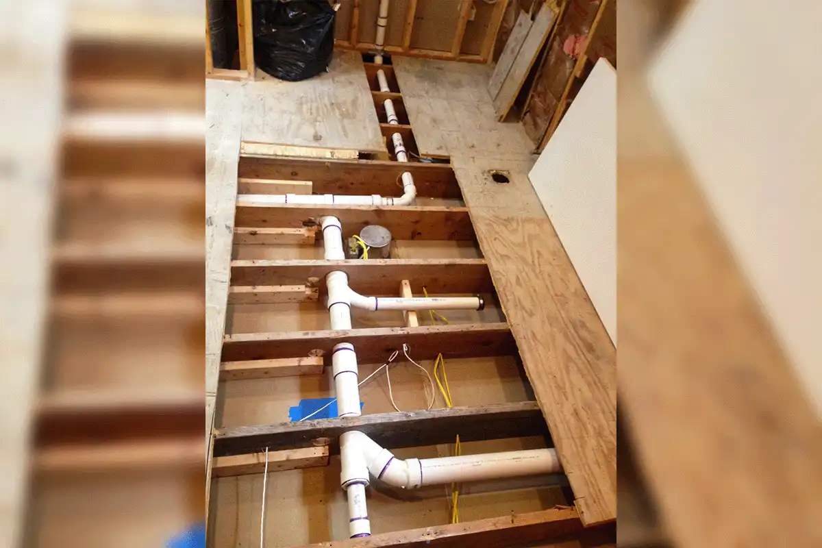 edp-toilet-repair-drain-rough-in-pvc-installation-2026 New PVC drain rough-in installation beneath subfloor showing toilet drain lines and connections during bathroom plumbing build-out — toilet installation Tampa — EVERYDAYPLUMBER.com Tampa Bay