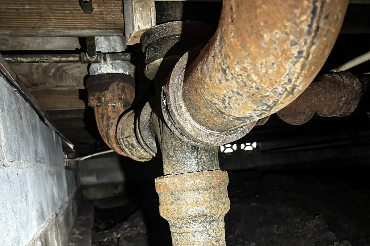 edp-corroded-cast-iron-crawlspace-2026 Corroded cast iron pipe fittings in a residential Tampa Bay crawlspace — residential sewer camera inspection — EVERYDAYPLUMBER.com Tampa Bay