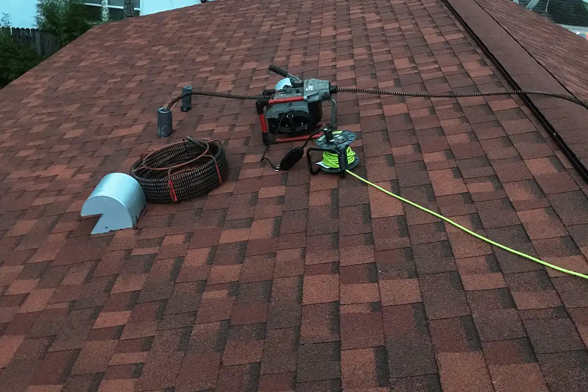 Drain cabling machine staged at a roof vent stack to clear a clogged line — residential drain cleaning — EVERYDAYPLUMBER.com Tampa Bay