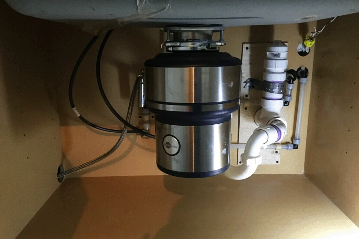 Newly installed garbage disposal mounted under a kitchen sink — garbage disposal installation — EVERYDAYPLUMBER.com Tampa Bay