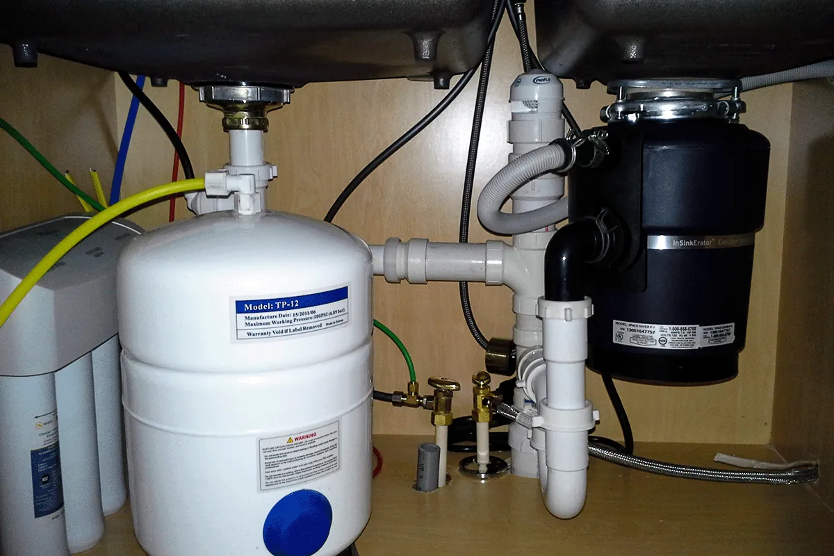 Garbage disposal installed beside a reverse osmosis water filtration tank under a kitchen sink — garbage disposal and water filtration — EVERYDAYPLUMBER.com Tampa Bay