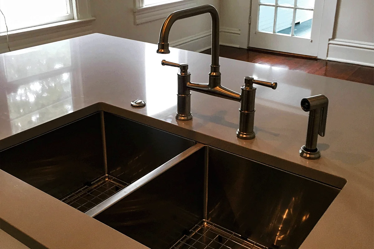 Stainless steel double-basin kitchen sink with bridge faucet installed in a Tampa Bay home — kitchen plumbing installation — EVERYDAYPLUMBER.com Tampa Bay