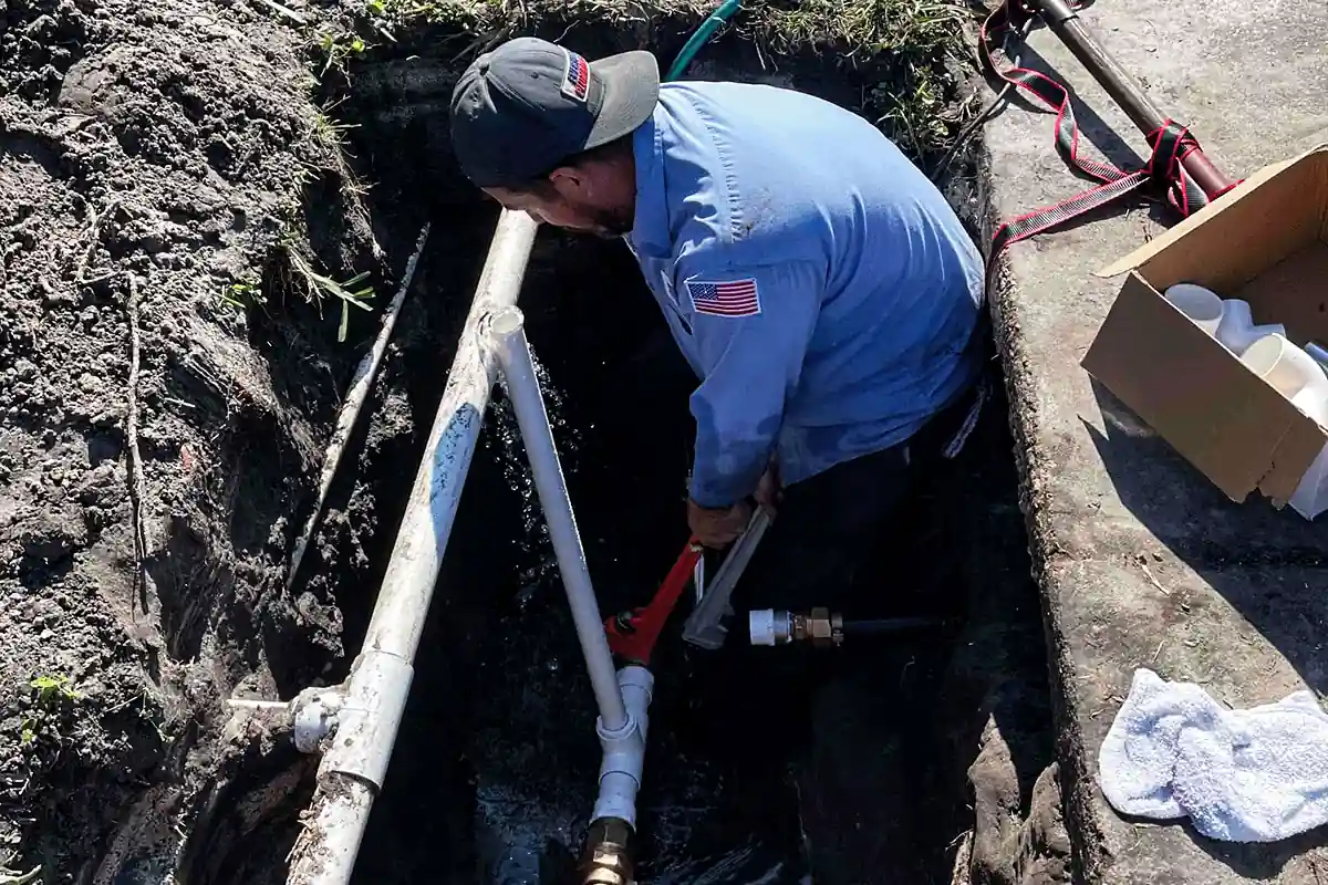 Plumber connecting a new water service line at the meter shutoff in an excavated trench — water line installation — EVERYDAYPLUMBER.com Tampa Bay